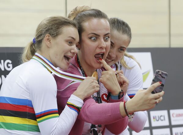 Российские спортсменки Анастасия Войнова и Дарья Шмелева позируют для селфи с неизвестной девушкой, завоевав золотую медаль в командном спринте среди женщин на чемпионате мира по велоспорту в Гонконге - Sputnik Lietuva