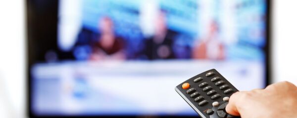 Мужчина держит пульт перед телевизором, архивное фото - Sputnik Литва