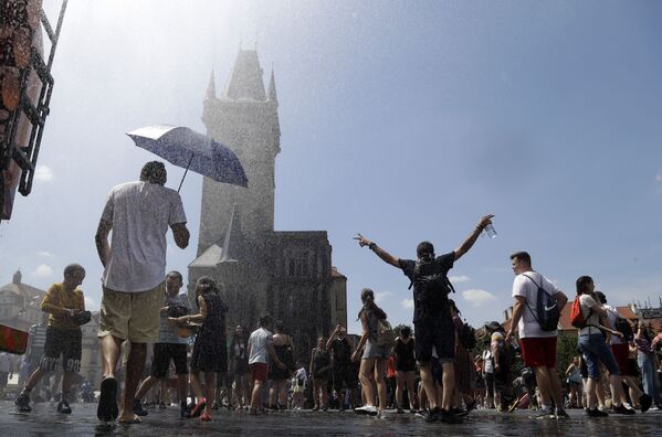 Люди охлаждаются под струей воды в жаркий и летний день на Староместской площади в Праге, Чехия - Sputnik Lietuva
