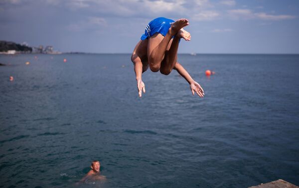 Отдыхающие прыгают с пирса на пляже в Ялте - Sputnik Lietuva
